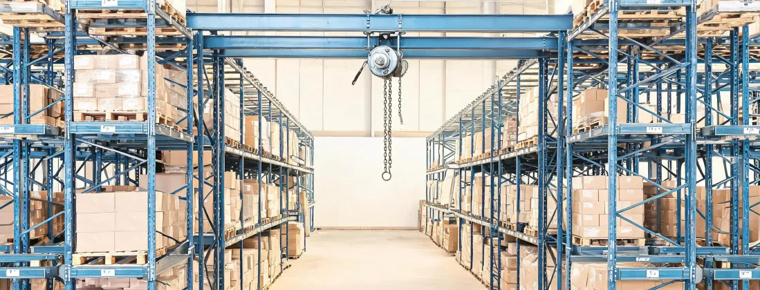 Illustrated warehouse aisle with a compact hand chain hoist